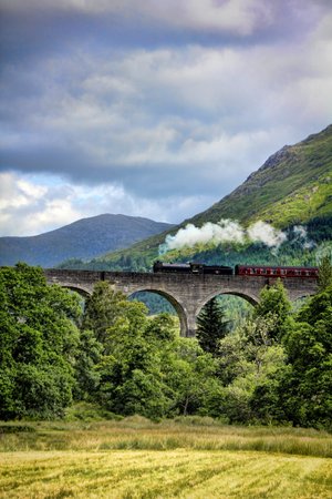 Stunning Landscape Photo of Mountains near Bridge Train and Hogwarts in Scotland  HD Wallpaper